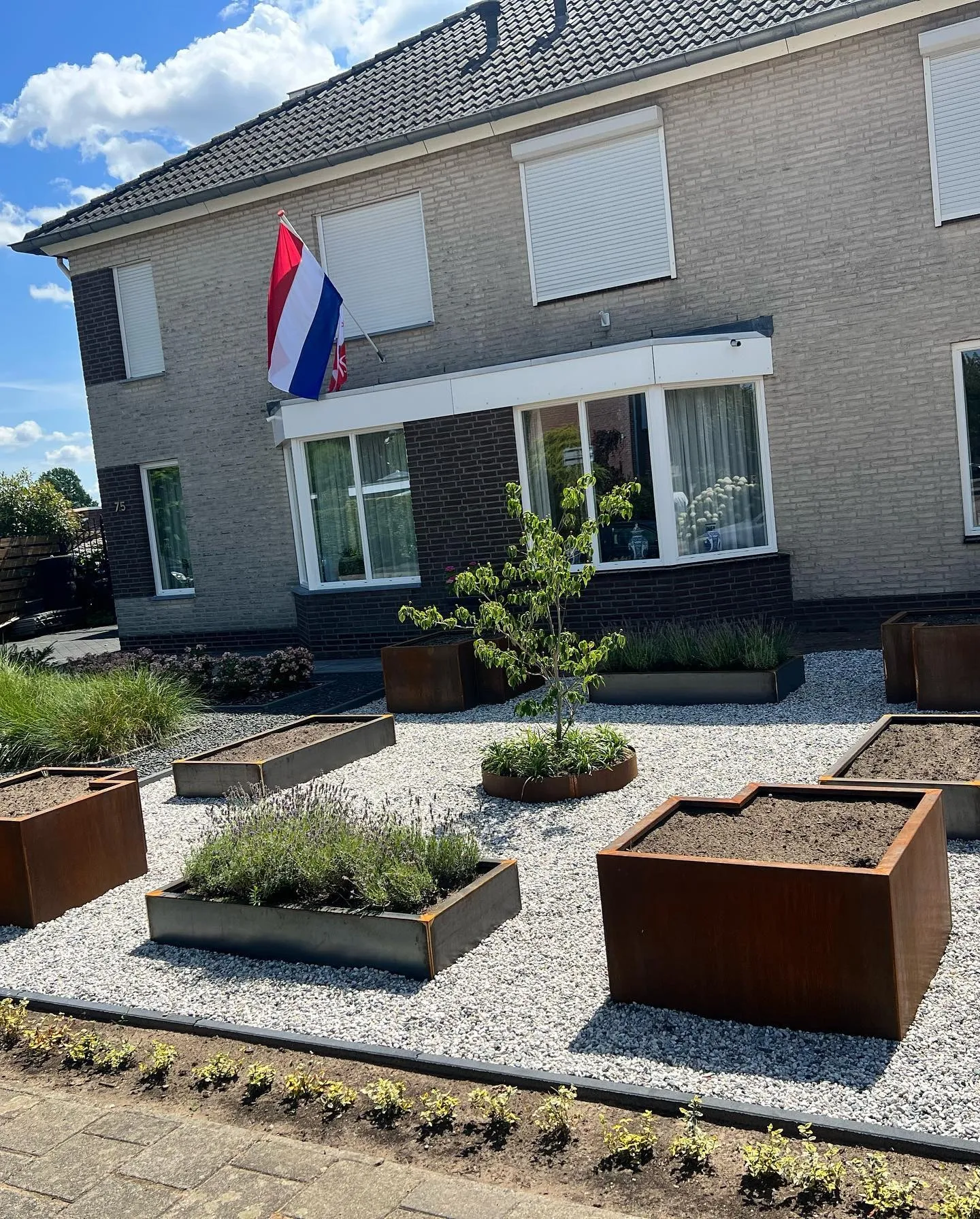 Cortenstalen bakken in een beplante voortuin