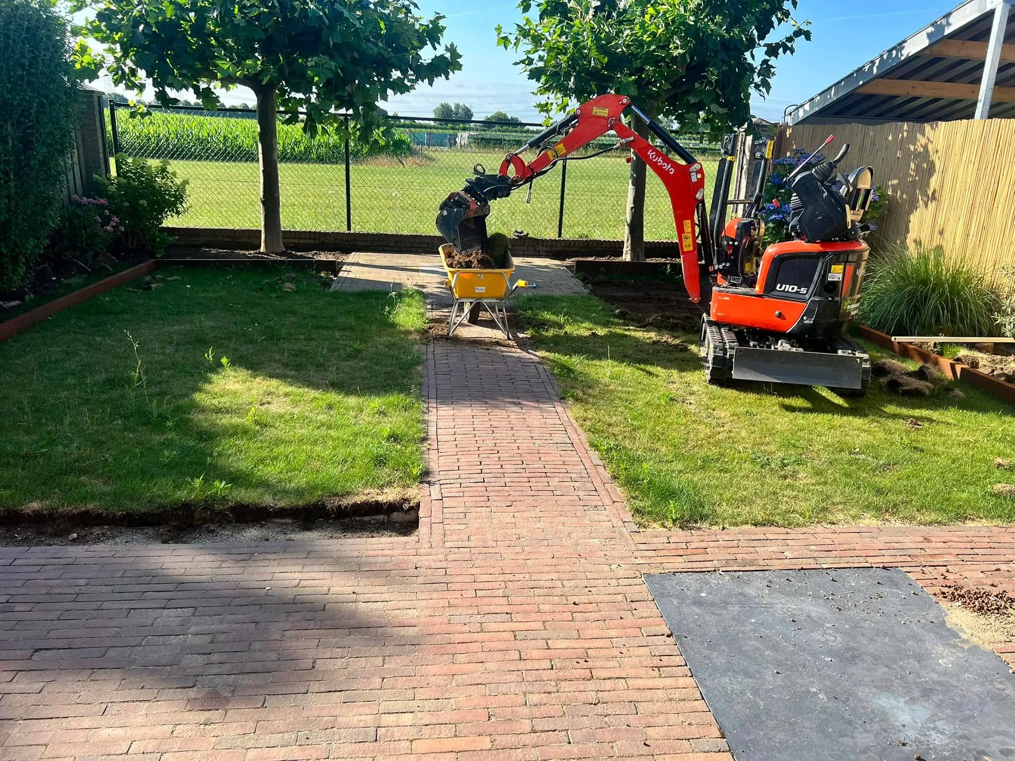 Minigraver naast het klinkerpad