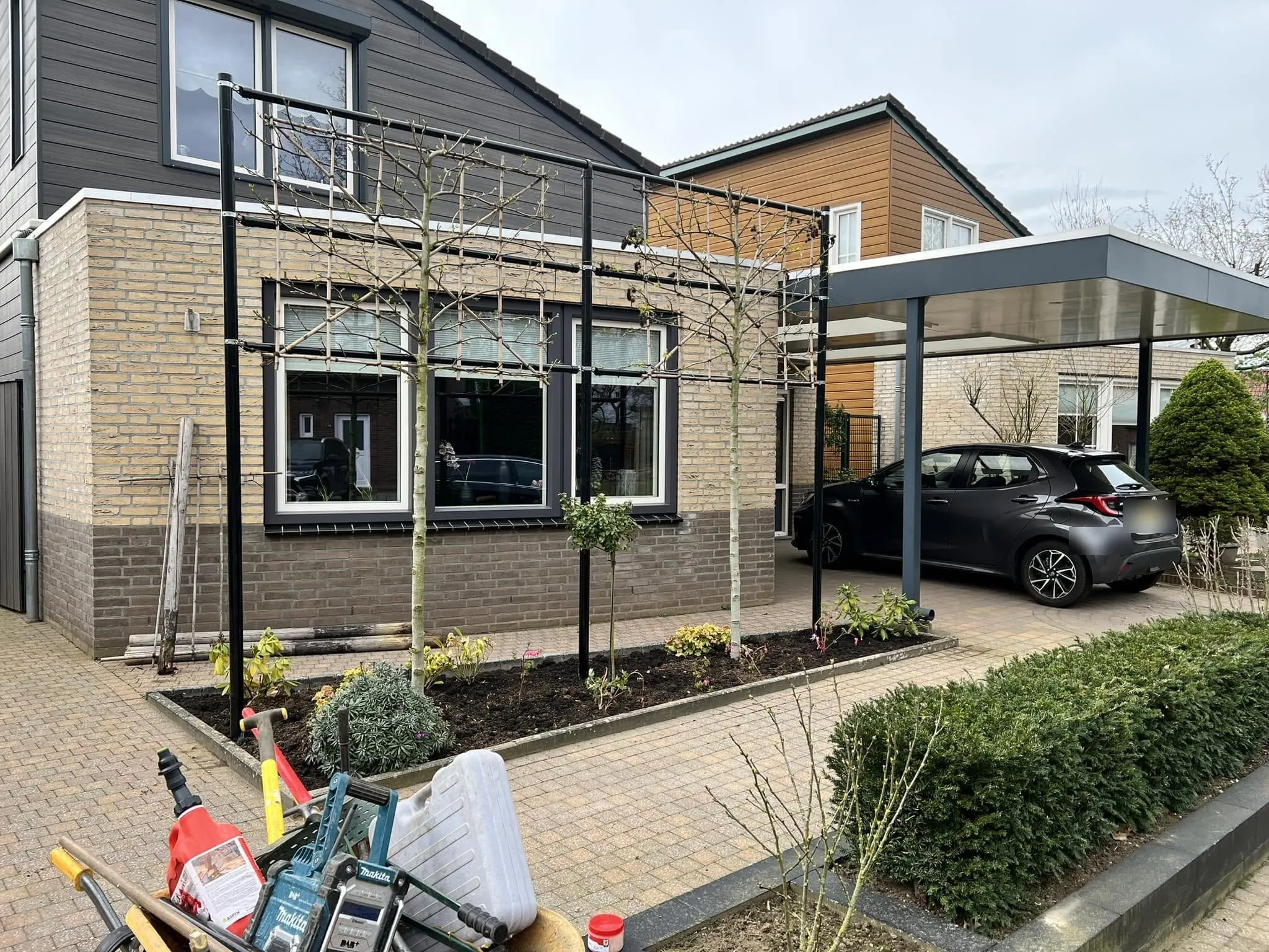 Voortuin met leibomen en carport